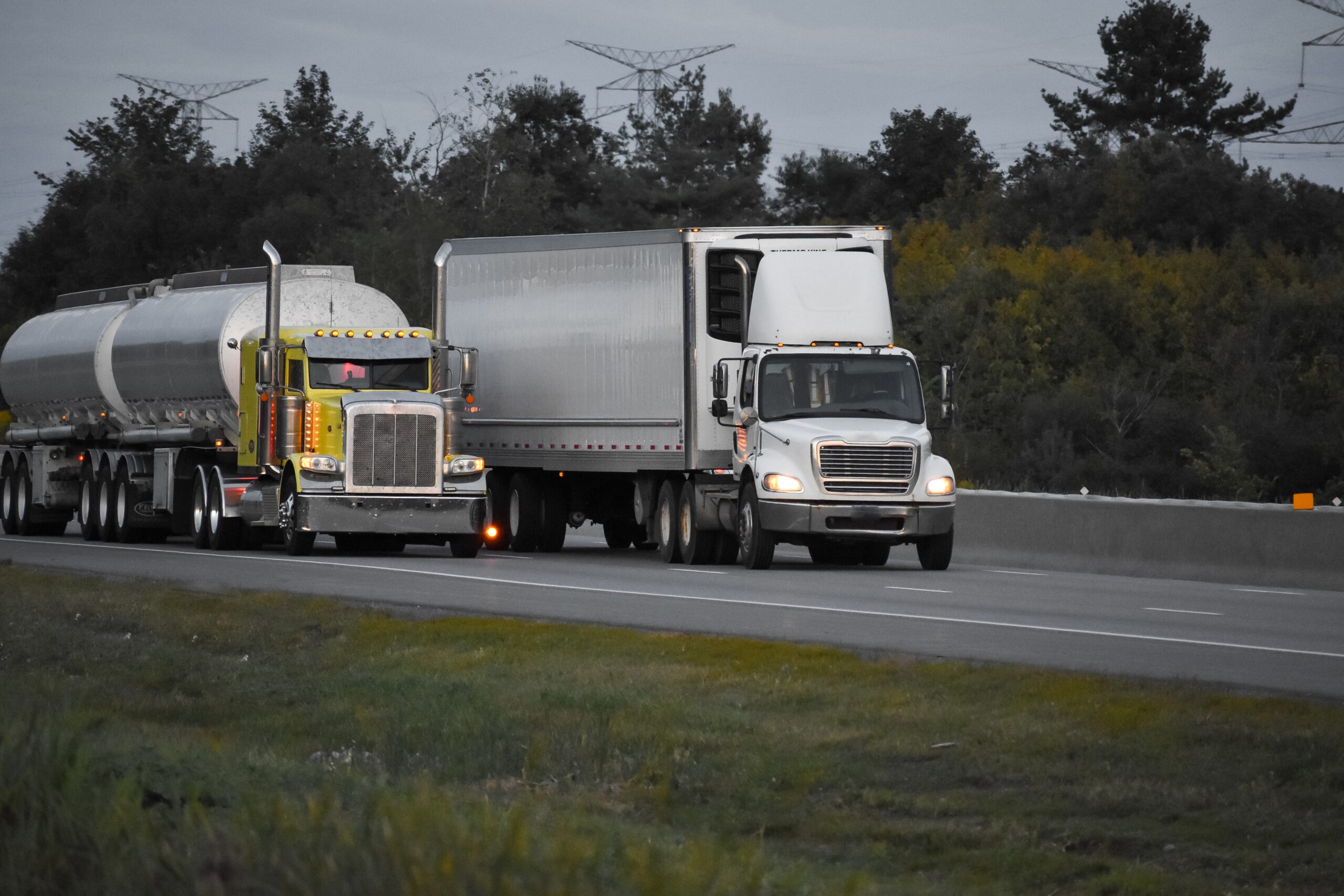 trailer trucks driving on the road surrounded by beautiful green trees